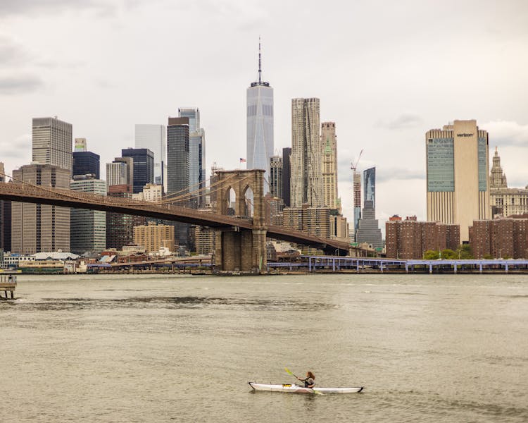 Man In A Kayak On A Body Of Water Along A City