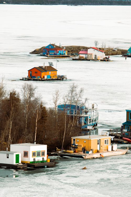Free Vibrant wooden floating houses on a frozen lake in winter with bare trees nearby. Stock Photo