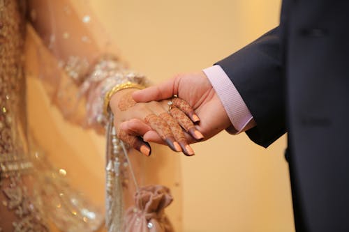 Man in Black Suit Holding Hands of Woman in a Bridal Dress