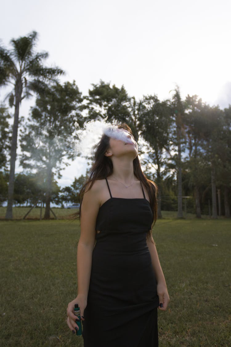 A Woman In Black Dress Smoking Vape