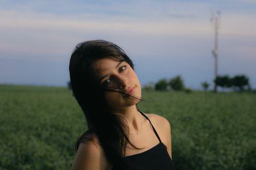 Free Portrait of a brunette woman in a black spaghetti strap top outdoors in a peaceful setting. Stock Photo