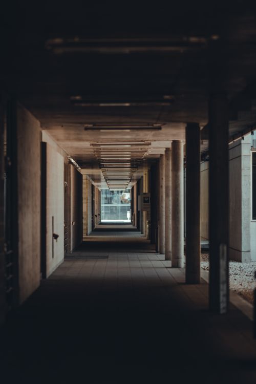 Free A dimly lit indoor hallway with pillars in a modern architectural style. Stock Photo