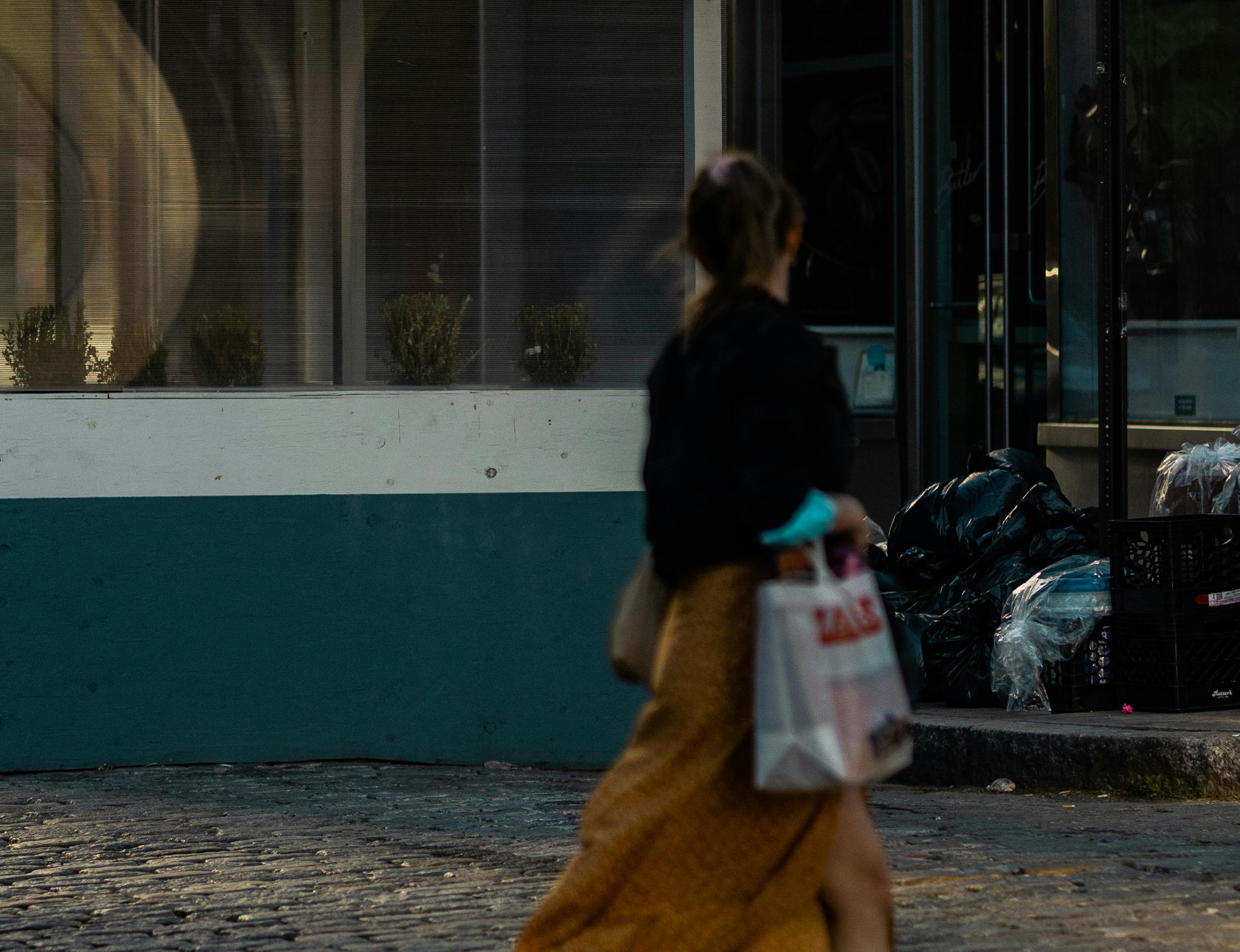 Person Walking On Sidewalk With Tommy Hilfiger Shopping Bag Stock