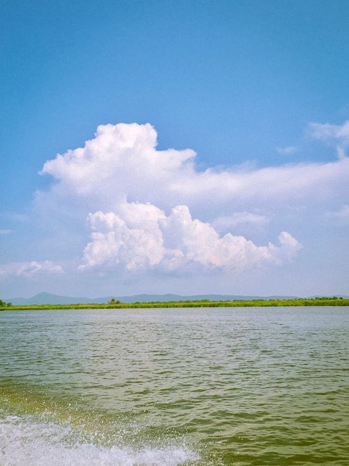 Free Serene lake view under a vivid blue sky with dramatic white clouds. Stock Photo