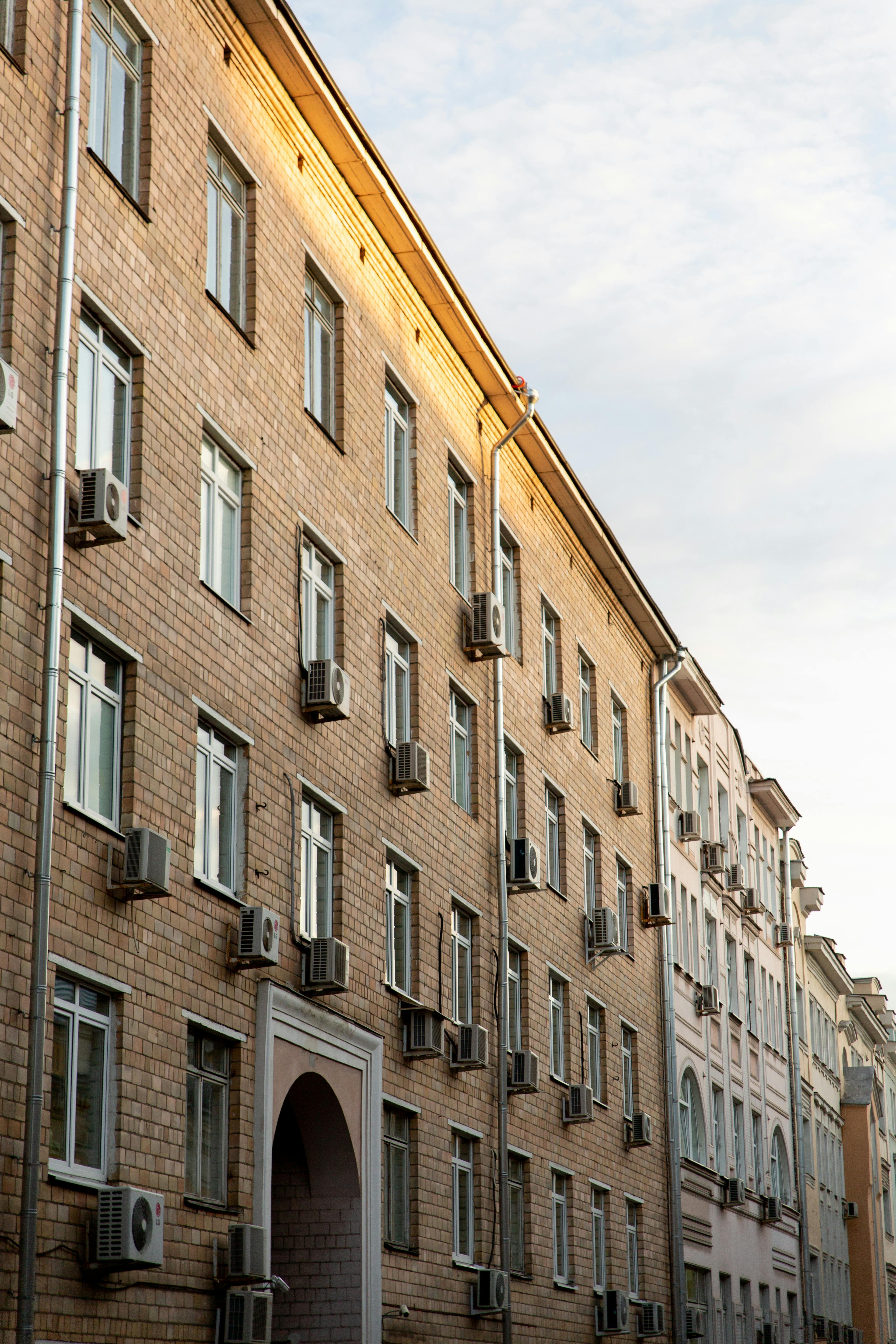 Row of urban apartment buildings with brick facades and air conditioning units.