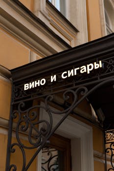 Ornate entrance sign reading 'wine and cigars' in Russian, on a classic building.