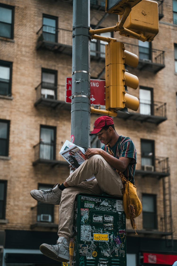 Man Reading Newspaper On Electrical Box