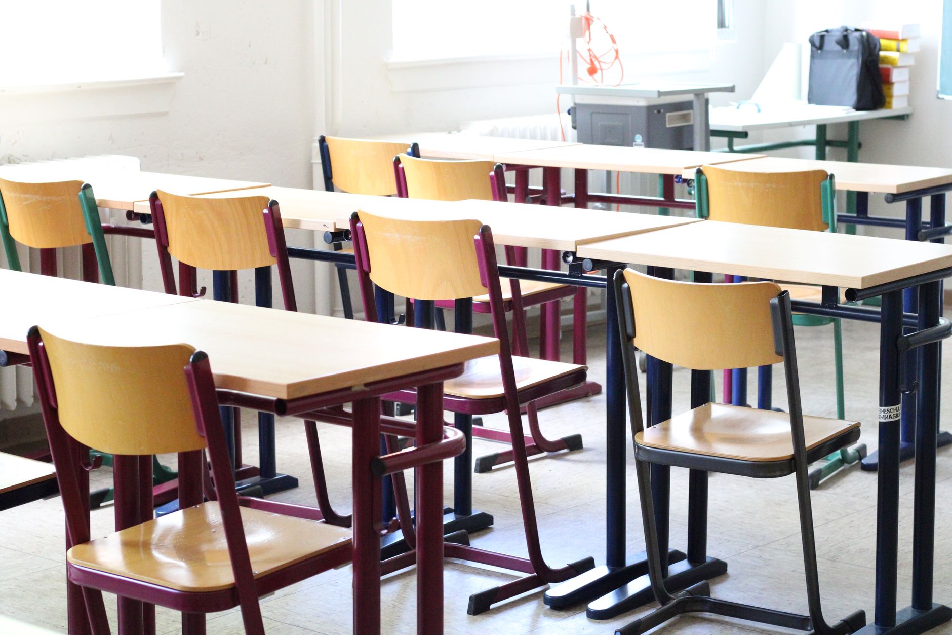 A bright empty classroom with wooden tables and chairs, ready for students.