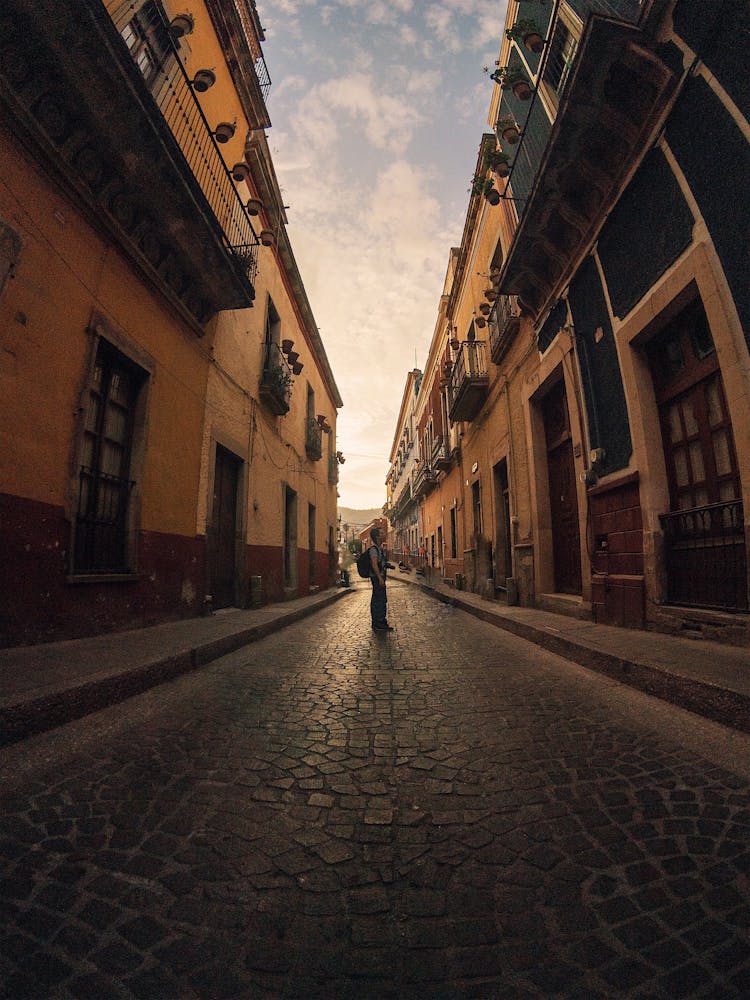 Man Standing On A Cobblestone Street