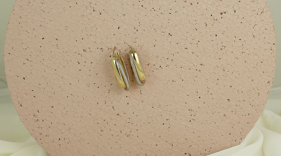 Boucles d'oreilles créoles dorées portées par une femme
