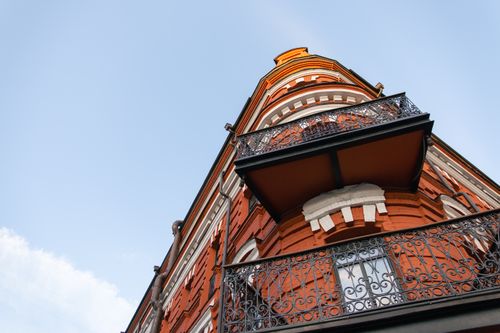 Free Low angle shot of a historic red brick building with ornate balconies against a clear sky. Stock Photo