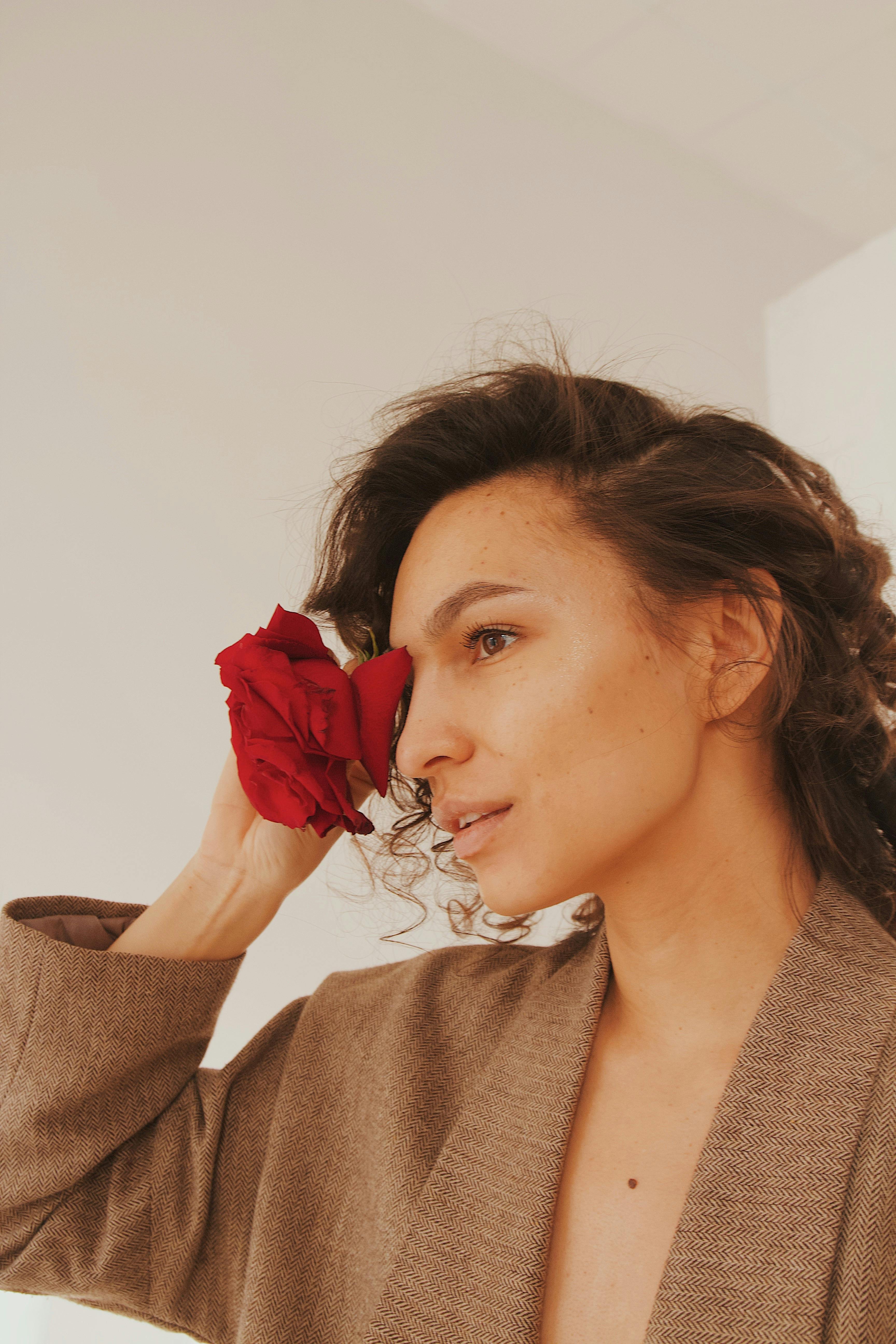 一位手持红玫瑰的女士的特写肖像，突显了美丽和优雅