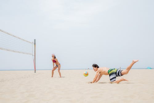 Laughing Man Falling During a Volleyball Game with a Woman