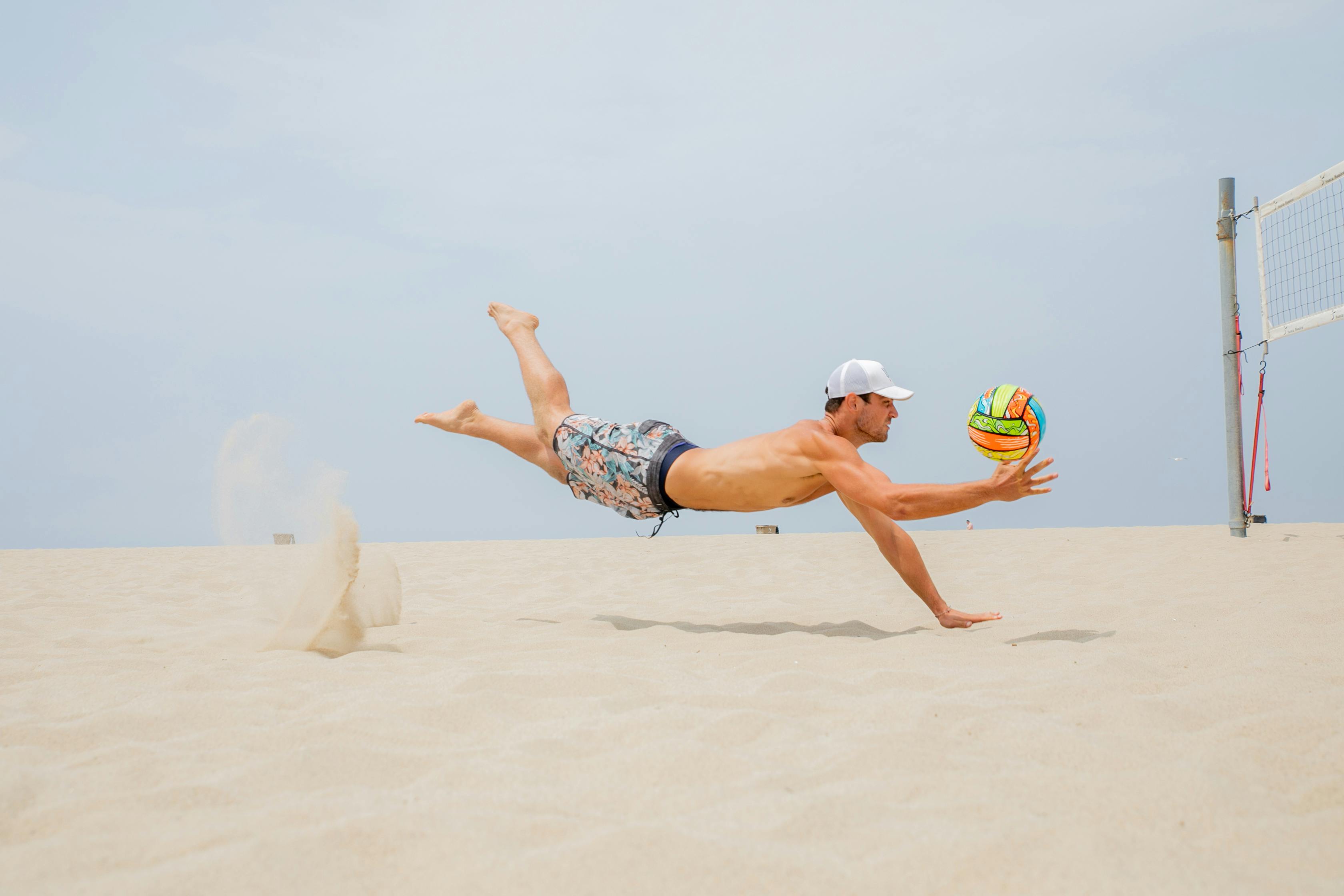 man midair playing beach volleyball