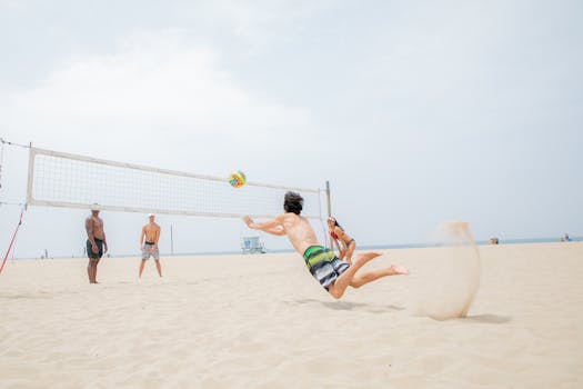 Exciting beach volleyball match with players midair diving for the ball on a sunny day.