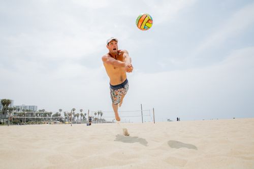 Free A man playing beach volleyball midair, showcasing intense focus and athleticism on a sunny day. Stock Photo
