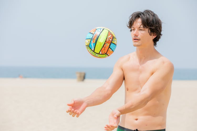 Man Throwing A Volleyball On A Beach