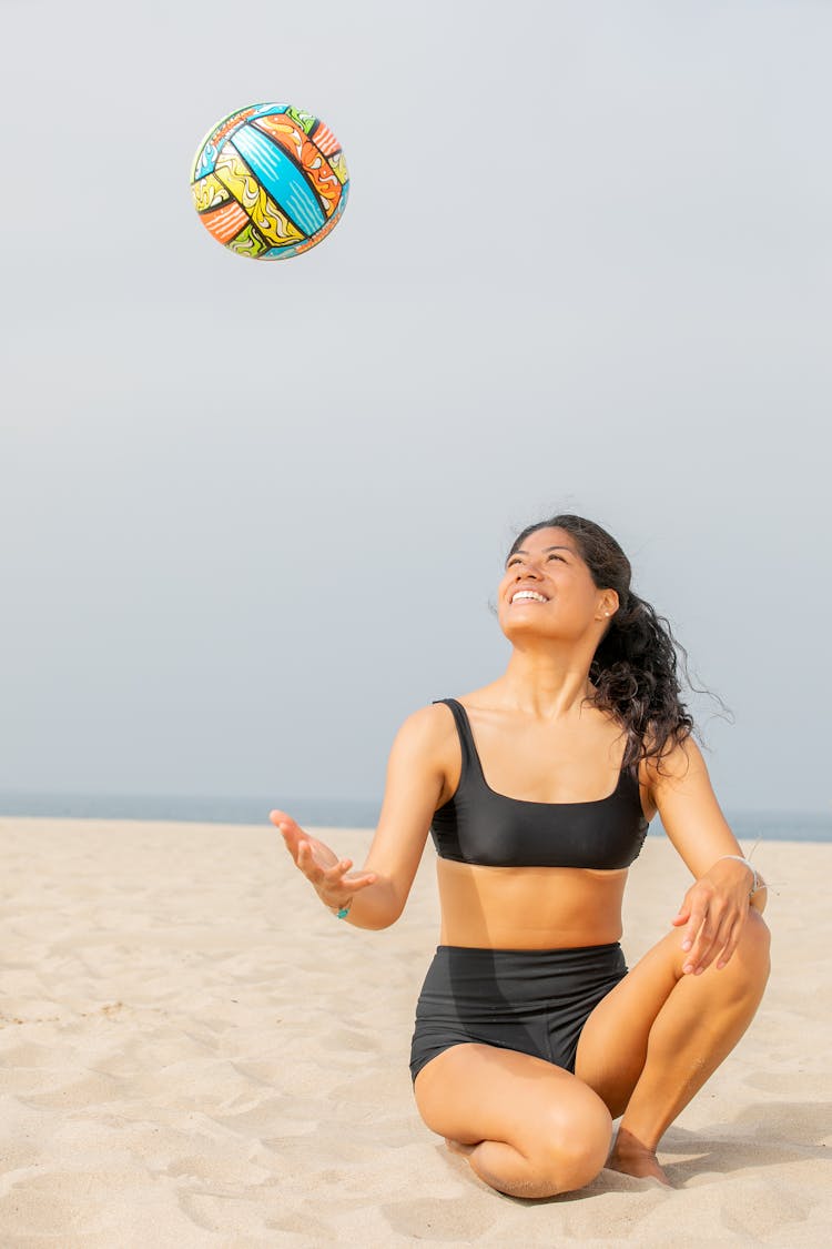 Woman On A Beach Tossing A Volleyball Ball