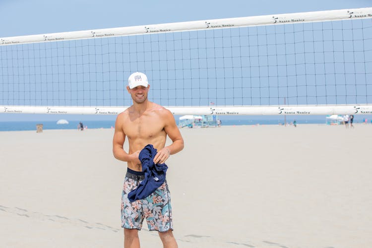 Young Smiling Man On Beach With Volleyball Net In Background