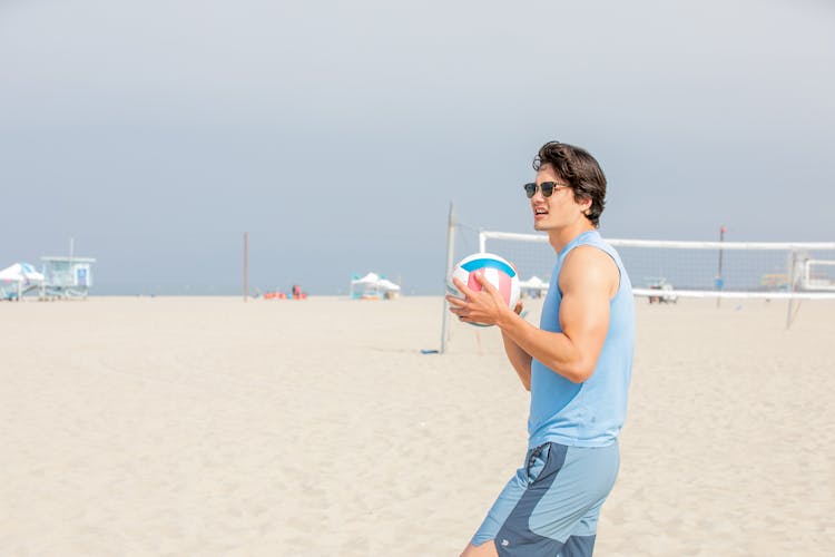 Man In Sunglasses Catching A Ball On A Beach