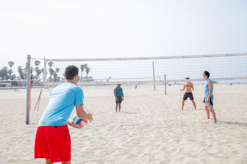 Free Friends playing beach volleyball, enjoying the sun and sand at the seaside. Stock Photo