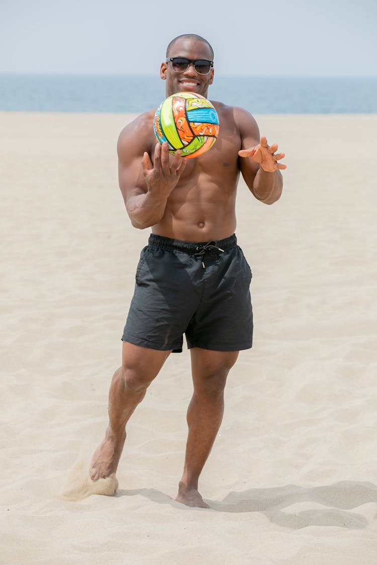 Man Tossing A Volleyball Ball On A Beach 