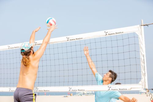 Free Two men engage in a competitive beach volleyball match under a clear blue sky at Santa Monica. Stock Photo
