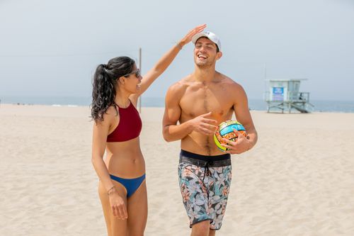 Free A happy couple plays beach volleyball, enjoying a sunny day by the sea. Stock Photo