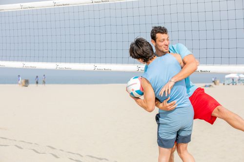 Free Two men enjoying a playful beach volleyball match on a sunny day by the sea. Stock Photo