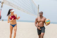 两名成年人在海边享受一场热闹的沙滩排球比赛
