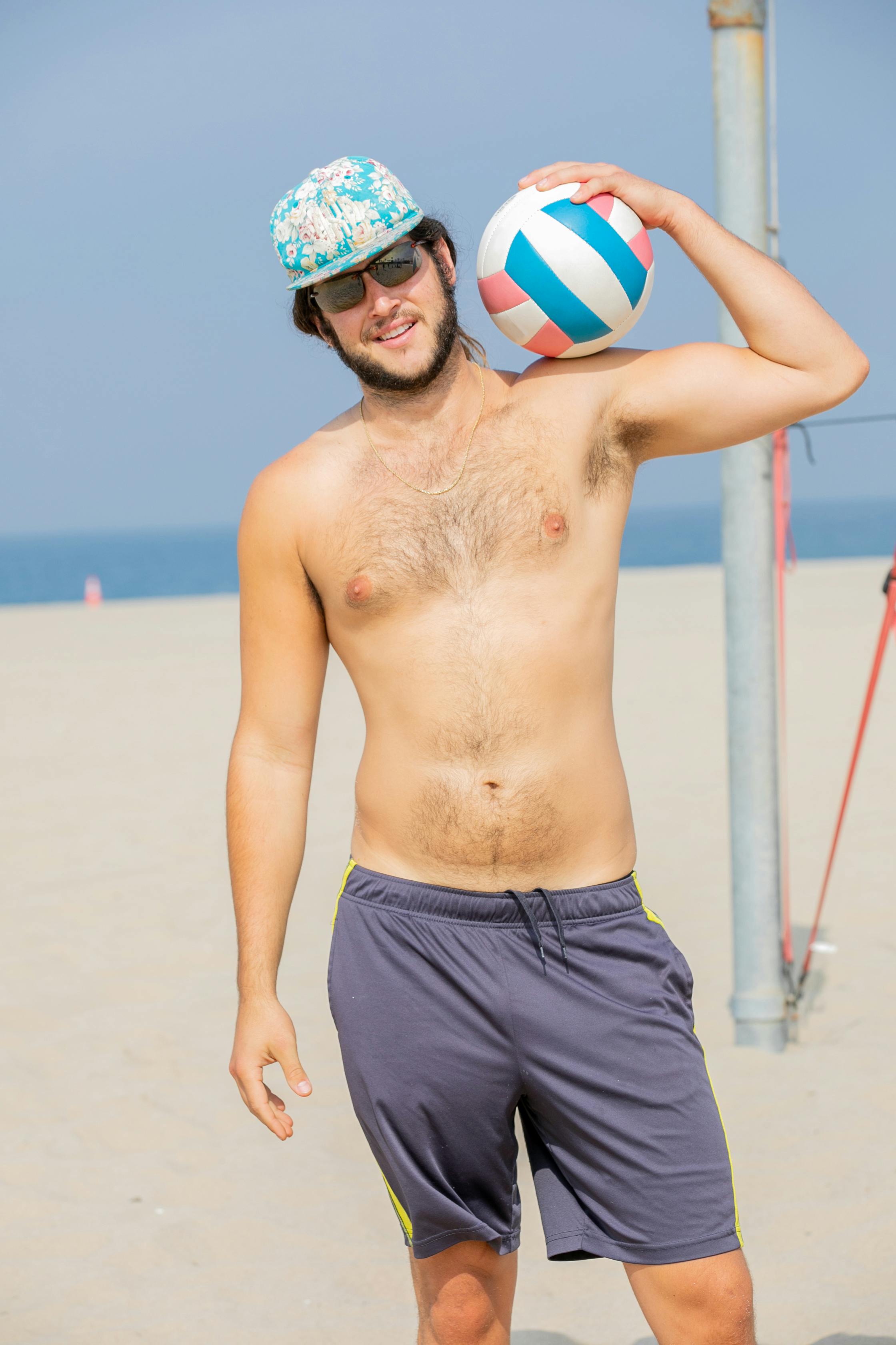 man posing on a beach with a volleyball ball