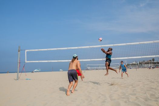Dynamic scene of friends playing beach volleyball on a sunny day at the coast.