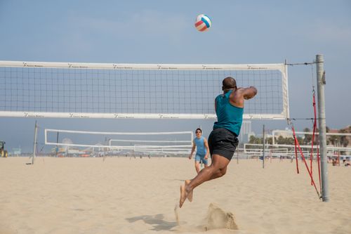 Free Dynamic beach volleyball game with players mid-jump at Santa Monica Beach. Stock Photo
