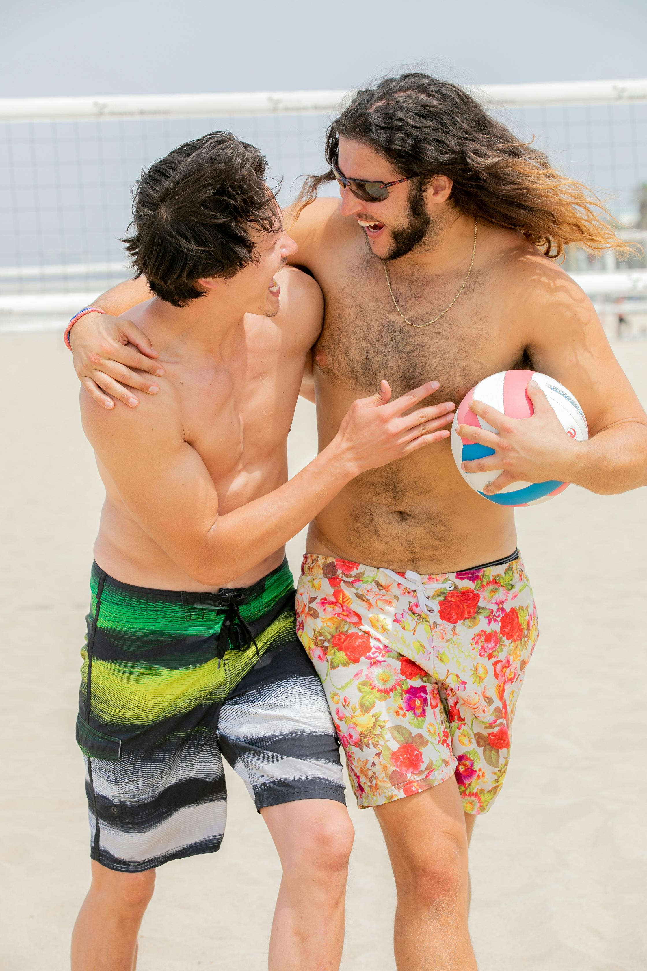 men with arms around each other running on a beach volleyball court