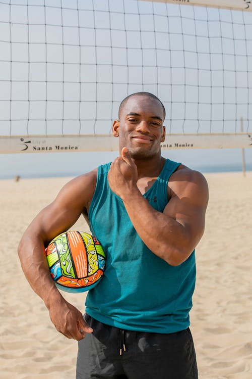 Free Man on a Beach Volleyball Court Holding a Ball Under His Arm and Smiling  Stock Photo
