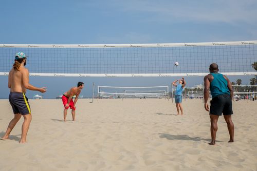 Free Four friends playing beach volleyball on a sunny day. Perfect for summer and travel themes. Stock Photo