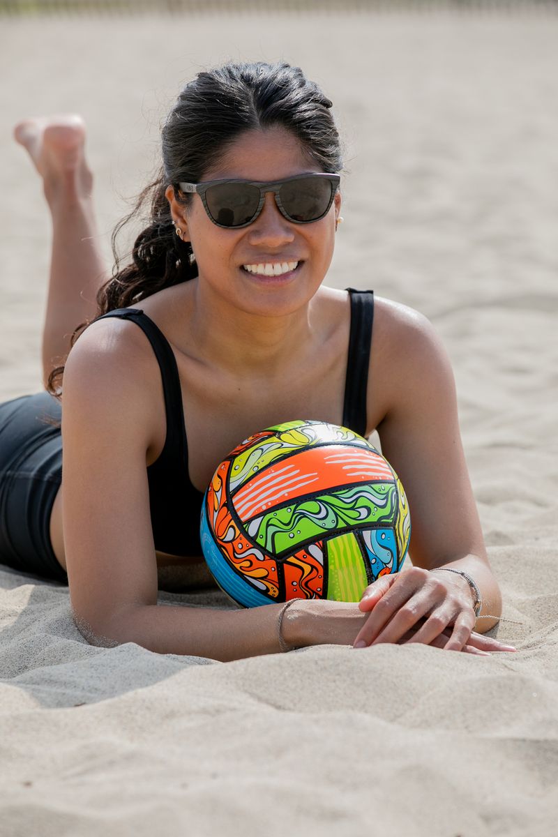 Joven disfrutando de un día soleado en la playa con una pelota colorida