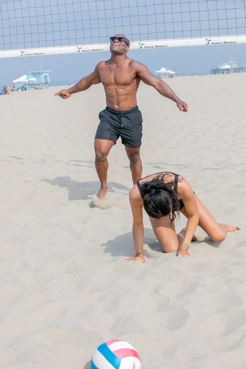 Free Energetic beach volleyball game with friends enjoying a sunny day by the ocean. Stock Photo