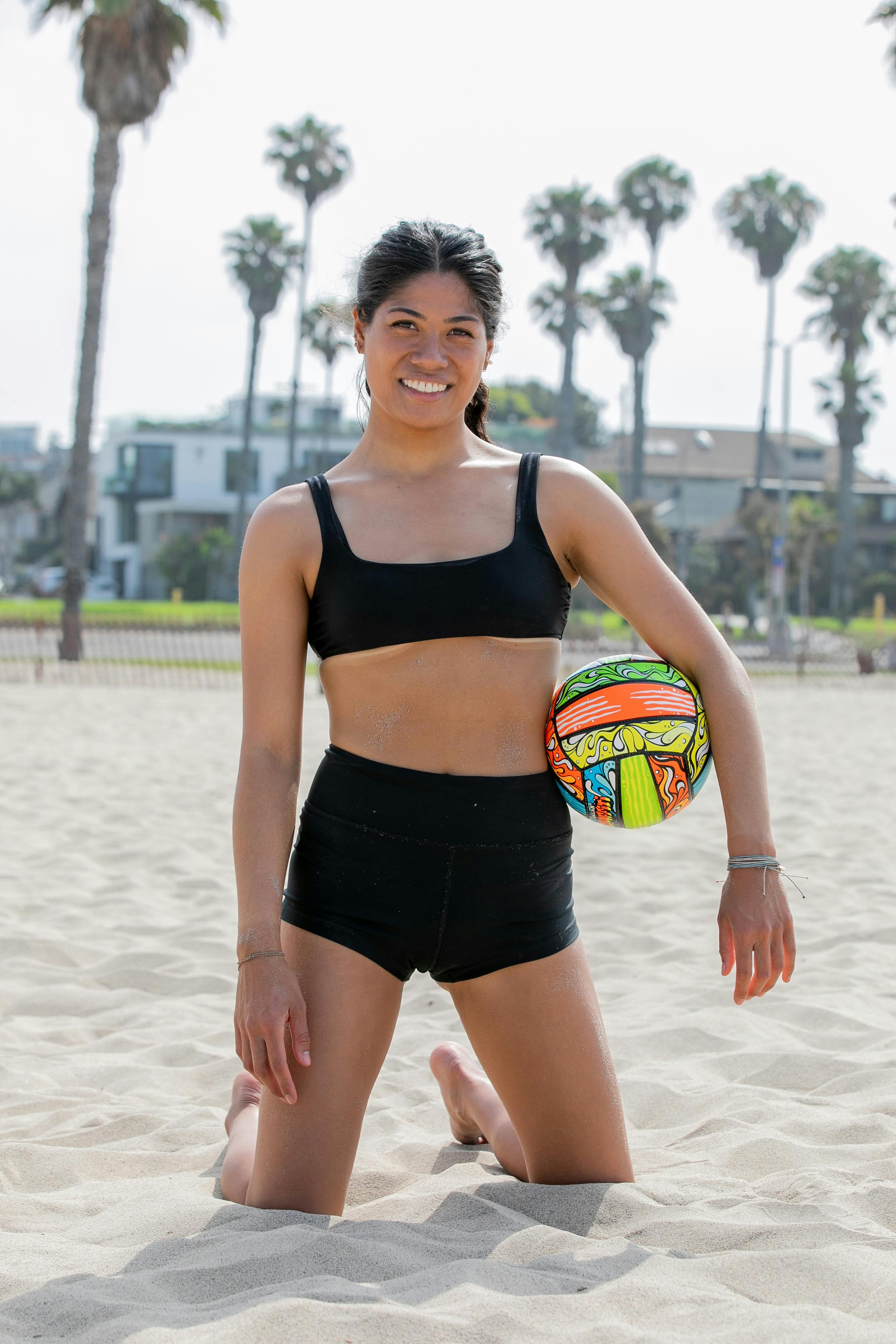 woman posing on a beach with a volleyball ball