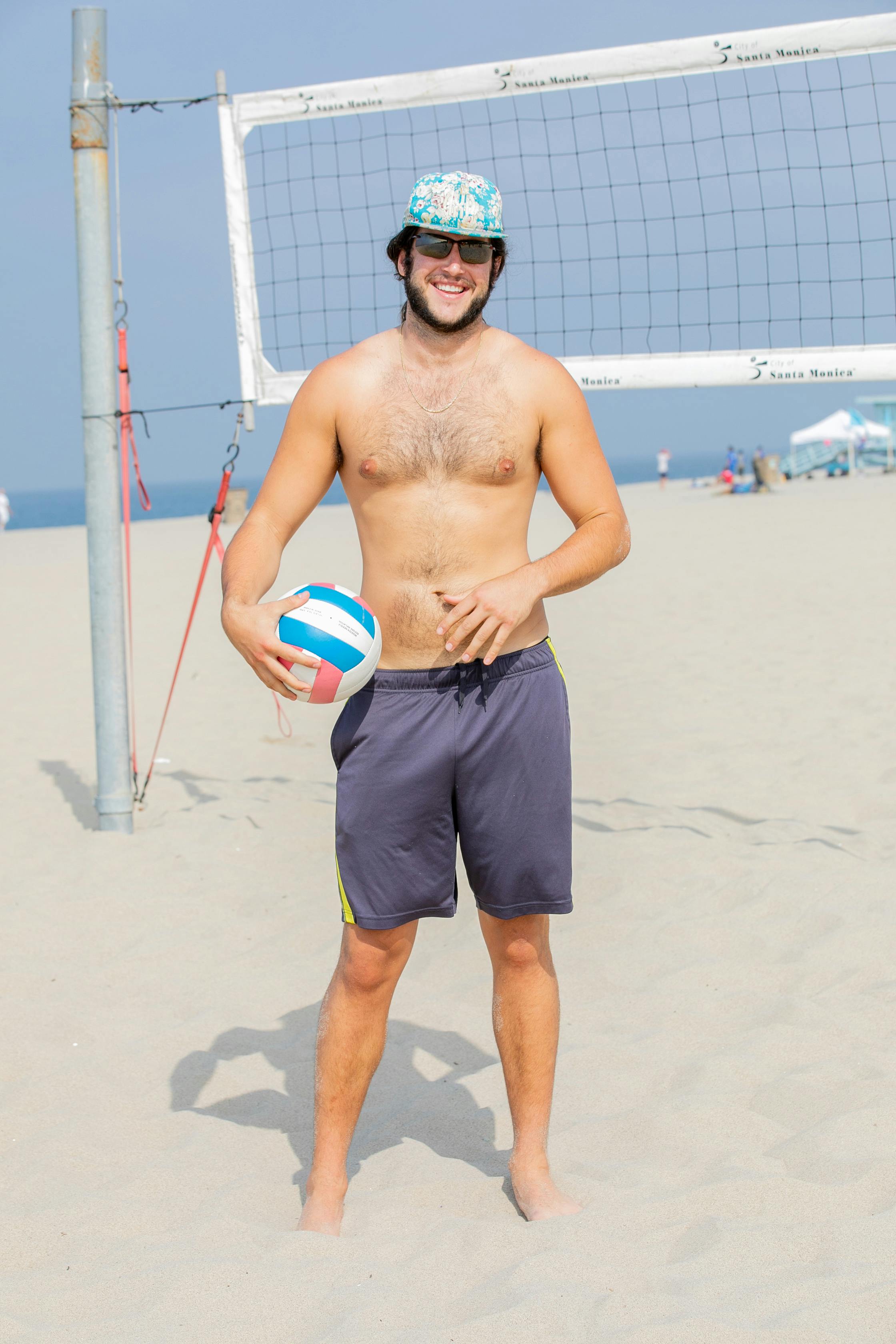 man posing on a beach with a volleyball ball