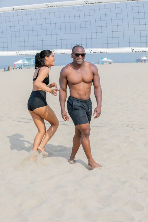 Free Joyful couple playing beach volleyball, enjoying a sunny summer day with laughter and fun. Stock Photo