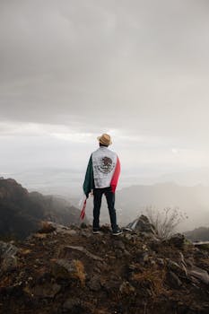 Back view of a man with Mexican flag overlooking mountains in San Juan Tlacotenco.