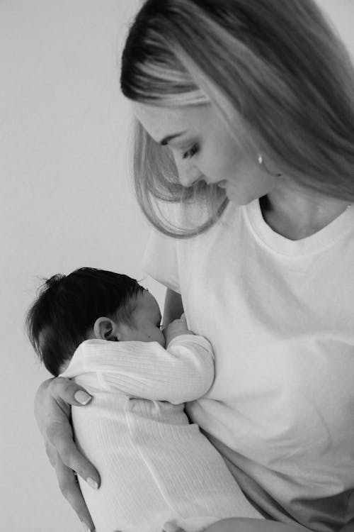 Grayscale Photo of a Woman Holding Her Newborn Baby