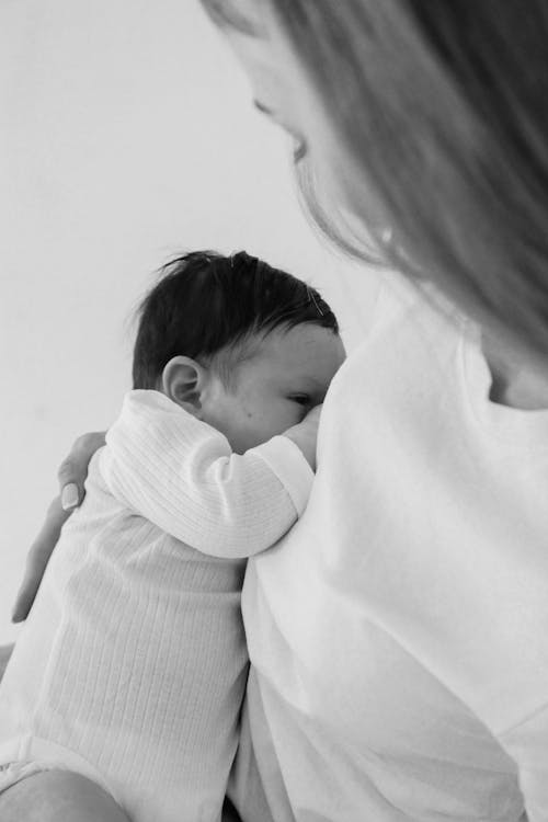 Free Woman in White Sweater Carrying Baby in White Long Sleeve Shirt Stock Photo