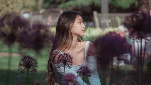 Free Young woman sitting in a lush summer garden surrounded by flowers. Stock Photo
