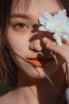 A beautiful close-up portrait of a woman holding a white flower, highlighting her natural beauty.