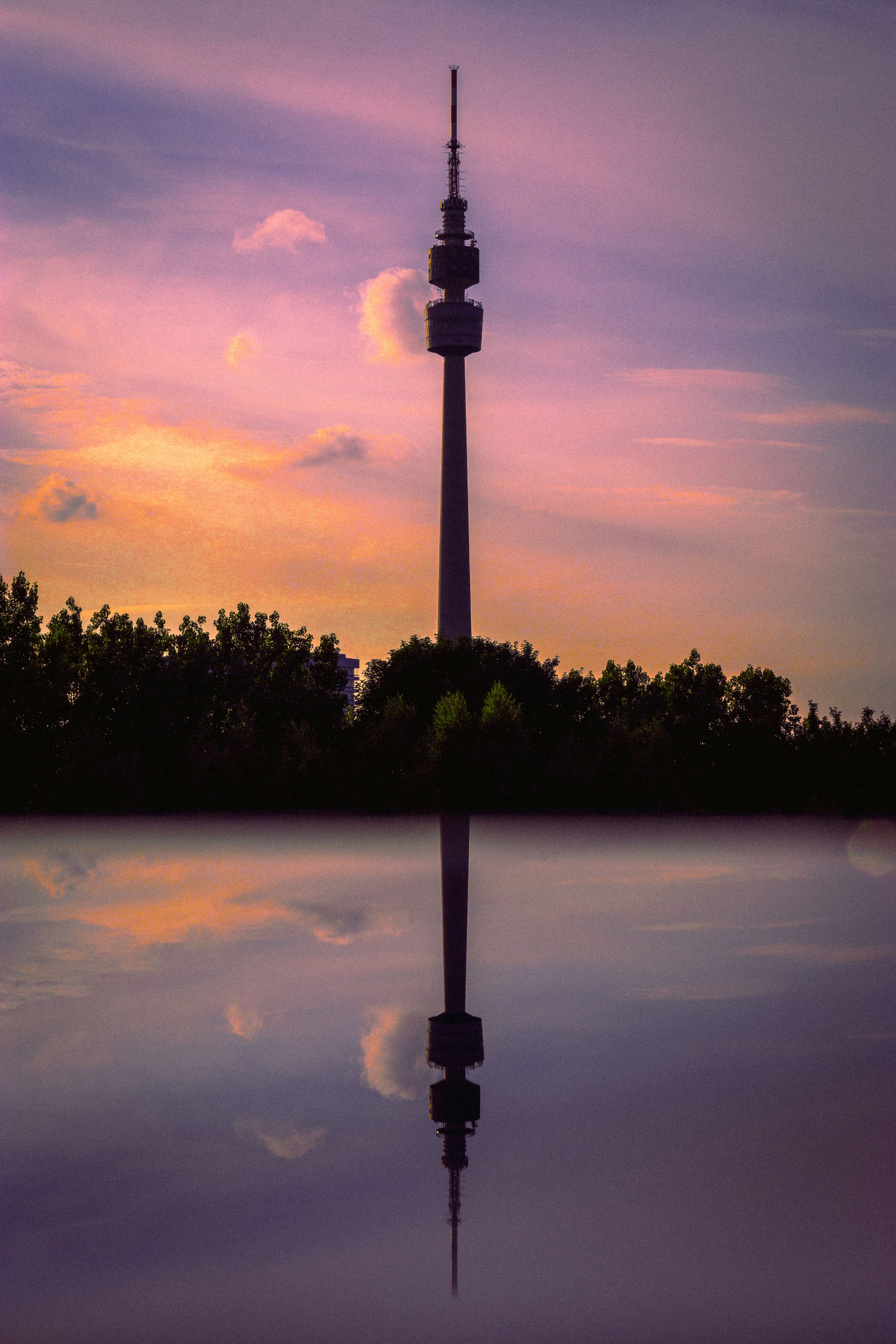 Stunning silhouette of the Florianturm in Dortmund reflecting over a calm lake at sunset.