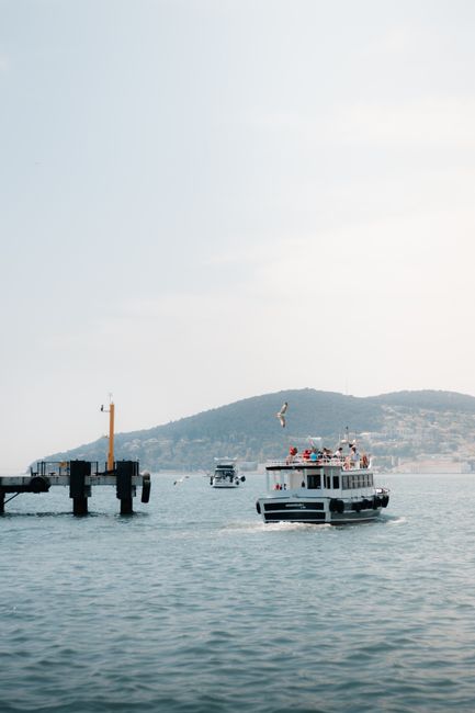A tranquil boat journey near a dock, set against the backdrop of distant hills on a clear day.