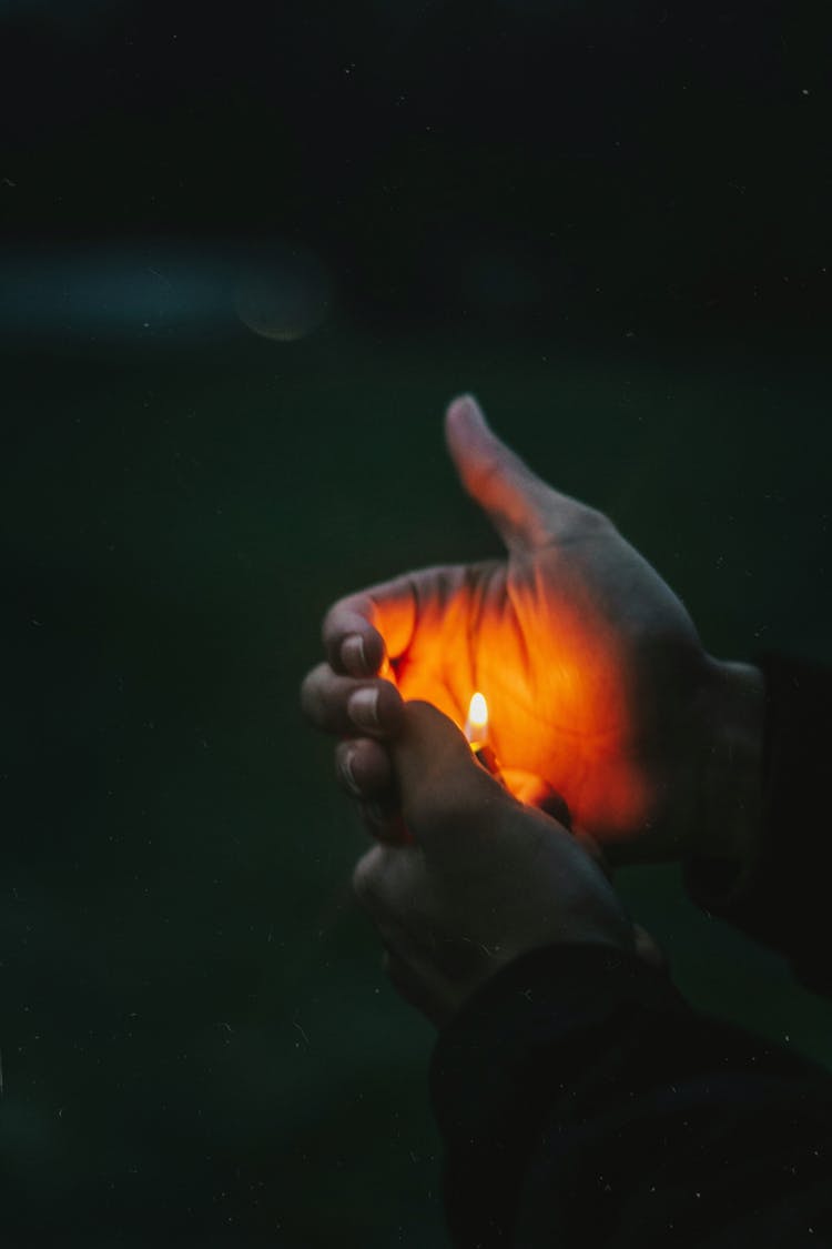 Hands Holding Gas Lighter In Darkness