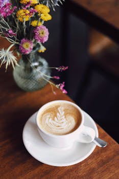 Beautiful latte art beside a vibrant floral arrangement in a Berlin café setting.
